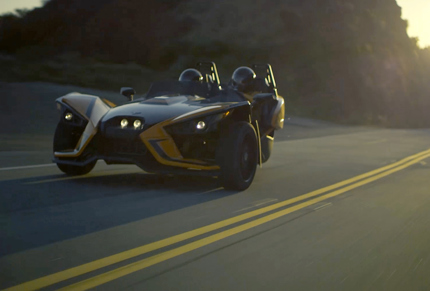 Two seat roadster driving down curvy road at dusk