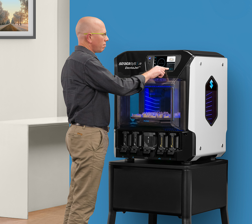 A man operating the J3 DentaJet 3D printer