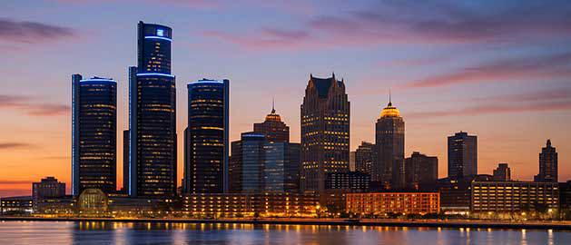 Detroit skyline at night with city lights reflecting on the river—representing Stratasys Direct’s 3D printing services for manufacturers across Michigan.