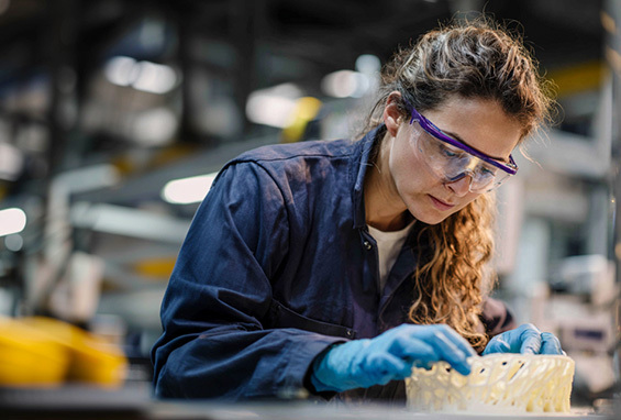 woman in safety glasses inspecting 3d printed part