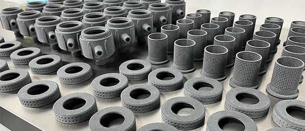SAF 3D printed parts all arranged in lines on a table